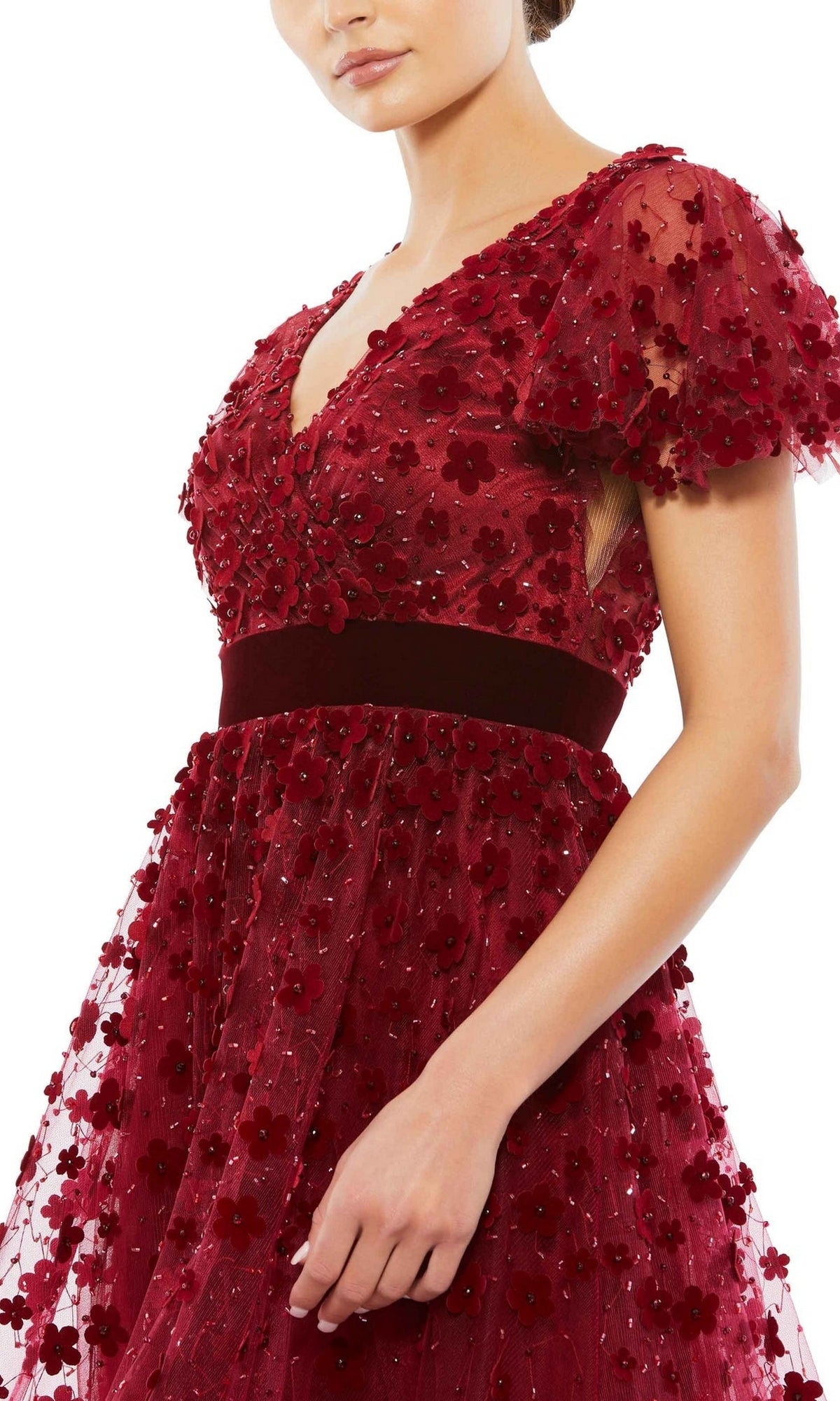A woman wears the Mac Duggal 67854 Floral Midi Wedding Guest Dress, a vintage-style deep red dress with short sheer sleeves, floral applique accents, and a velvet band at the waist.